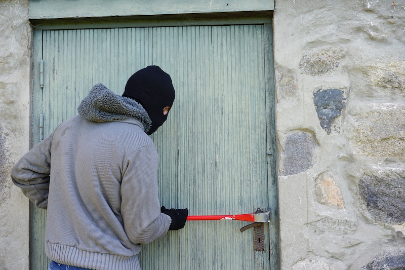 Einbrecher mit Brechstange an einer Tür