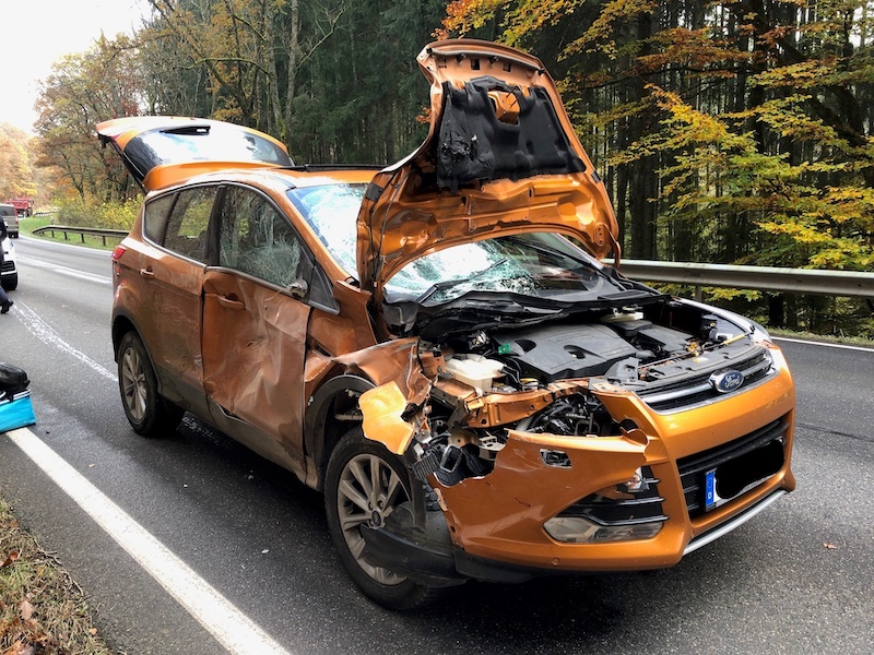 Orange farbener SUV mit Totalschaden steht auf einer Straße